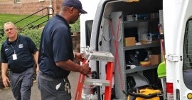 Two men getting ladder and equipment out of van